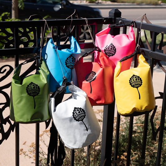 Various colors of dry bags with Odell Brewing logo